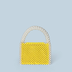 Detailed view of handmade woven yellow bead handbag with white pearl-like handle accents