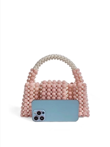 Pink and white handmade beaded handbag shown next to a smartphone for size reference