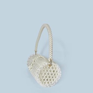 Detail of hand-woven pearl bucket bag with gold rings and elegant wavy bead texture