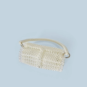Detail of hand-woven pearl beaded handbag with large pearl clasp and gold rings