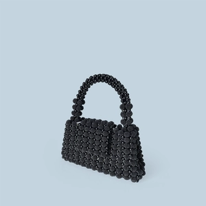 Detail of hand-beaded black vintage handbag with glossy textured finish and top handle