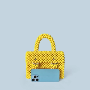 Détail d'un sac à main artisanal en perles jaunes avec un motif de visage souriant