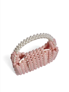 Close-up of pink beaded handbag featuring elegant white pearl handles and satin lining