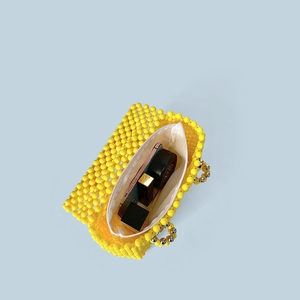 Vue de dessus du sac à main perlé jaune montrant l'espace pour rouge à lèvres et mobile