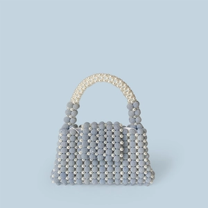 Detail of blue and white handmade beaded tote with a pearly white handle and zipper