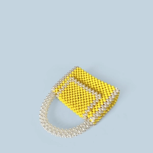 Macro shot of yellow woven beads with pearl accents on a stylish mini top-handle bag