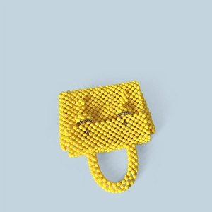 Détail d'un sac à main en perles jaunes avec accents argentés et texture tissée