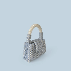 Detail view of handmade light blue beaded handbag with white pearl floral accents