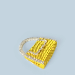 Detail of handmade yellow and pearl white beaded trapezoid handbag on light grey background