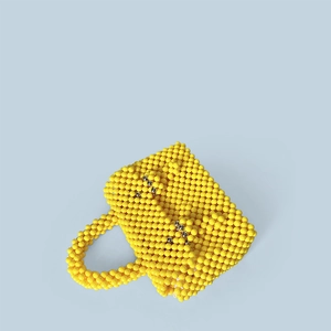 Détail du sac à main perlé jaune fait main avec accents argentés et poignée tissée