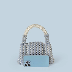 Macro shot of blue and white beaded handbag with a smooth silver zipper and pearl texture