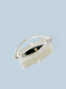 White pearl beaded handbag with top handle and zipper closure on a light blue background
