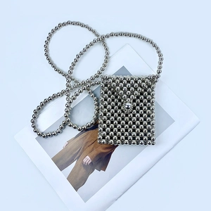 Close-up of handmade silver beaded mini crossbody bag on a fashion magazine background