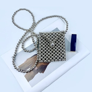 Detail of silver beaded mini crossbody bag featuring metallic woven beads and chain strap