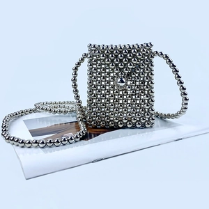 Detail of silver handcrafted beaded crossbody bag with glossy metallic finish and beads
