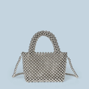 Close-up of handmade silver metallic beaded handbag with woven texture and handle