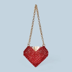 Détail du sac perlé rouge en forme de cœur avec chaîne dorée et doublure satinée