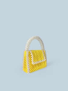 Handmade woven yellow mini square bag with white bead accents on a light blue background