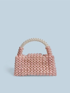 Pink beaded handbag with white pearl handle and textured floral clusters on blue background