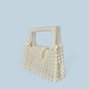 Detail of handmade pearl beaded handbag with large button closure and woven texture