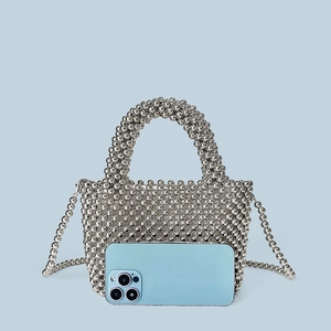 Detailed view of silver metallic bead tote bag shown with a phone for size comparison
