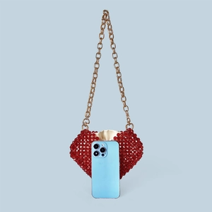 Détail du sac cœur en perles rouges avec chaîne dorée et smartphone pour la taille