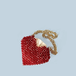 Détail du sac perlé rouge en forme de cœur avec doublure en satin et chaîne dorée