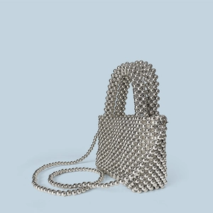 Detailed view of silver metallic beaded handbag with high-shine woven texture and strap