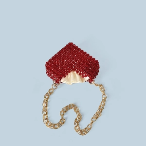 Détail du sac à perles rouge en forme de cœur avec bandoulière dorée et satin