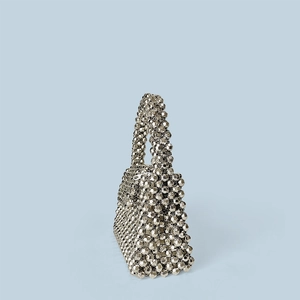Gros plan d'un sac enveloppe tressé en perles argentées avec texture géométrique