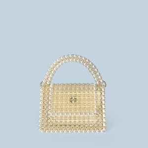 Detailed shot of yellow beaded handbag with pearl accents and a golden clover clasp