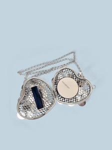 Detail view of silver heart-shaped mesh bag showing capacity with lipstick and cushion