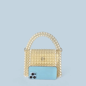 Mini handmade pearl beaded handbag with metallic flower clasp next to a smartphone