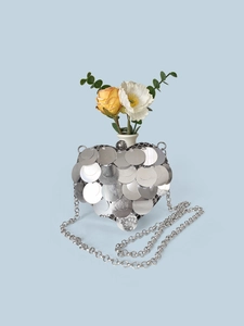 Macro detail of heart-shaped silver sequin bag with floral decor and chain strap