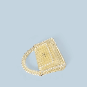 Detailed view of handmade beaded handbag with white pearls and yellow beads on blue background