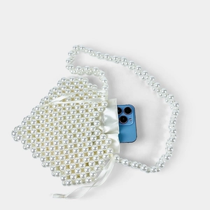Detail view of pearl beaded mini handbag with drawstring liner and phone for size scale