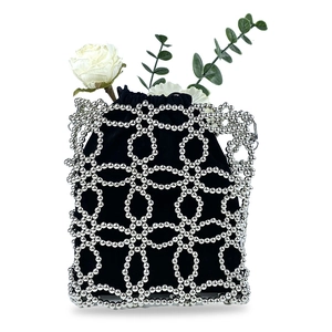 Macro shot of silver beaded metal frame with black velvet drawstring pouch and rose