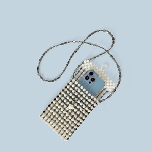 Dettaglio borsa a tracolla in perline fatta a mano con catena in metallo su sfondo blu