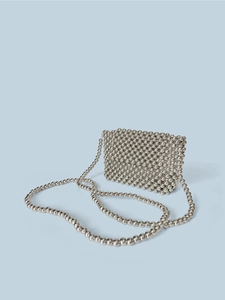 Detail of a handmade silver beaded crossbody bag featuring a woven metal bead flap design