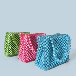 Detail of handcrafted beaded handbags in green, pink and blue with faceted bead texture