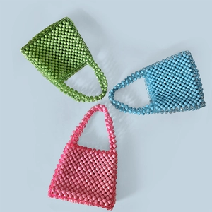 Close-up of handmade beaded handbags in pink, green, and blue with stylish top handles