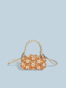 Detail van amber kristallen kralen en witte parelketting op een mini kralentasje