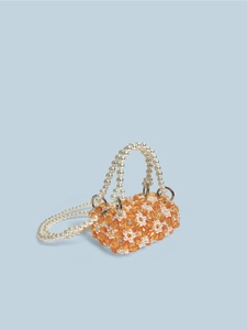 Detail van handgemaakte kralen minitas met oranje geometrisch patroon en parelriem