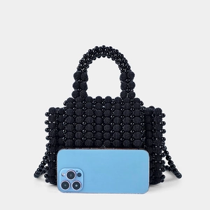 Detail der schwarzen Perlenhandtasche mit handgefertigter Textur neben Smartphone