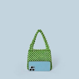 Detail of green beaded mini handbag showing texture next to a smartphone for size