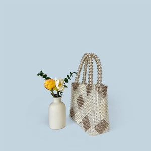 Detail of handmade beaded tote bag featuring a brown and white argyle diamond pattern