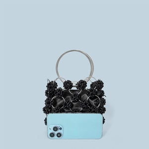 Mini black beaded handbag with metallic rings and satin lining next to a smartphone