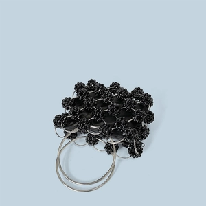 Detail of handmade black beaded handbag featuring metallic silver ring handles and accents