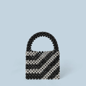 Close-up of handmade beaded bucket bag with black and silver diagonal stripes and pearl handle