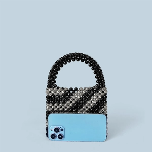 Detail of a handmade beaded bucket bag in black and silver with a smartphone for scale